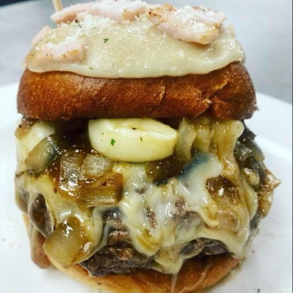 Close-up of a Rock Burger with melted cheese, caramelized onions, and garlic cloves.
