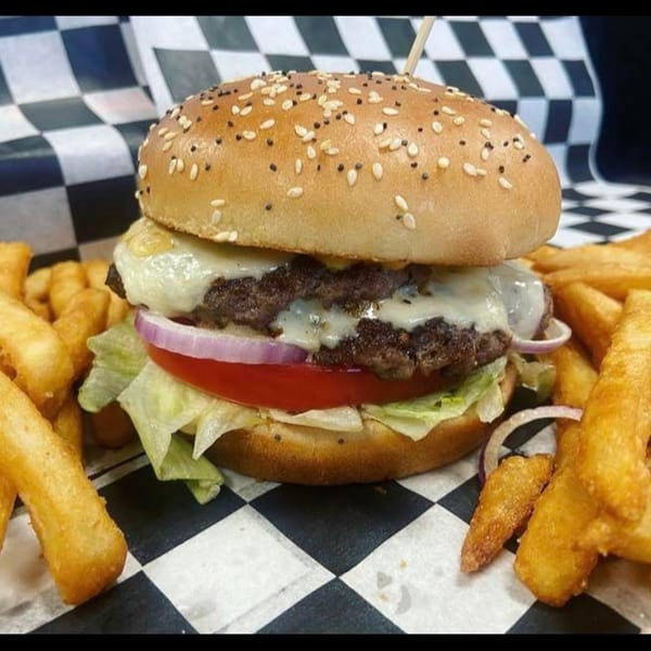 Rock Burger's double cheeseburger with lettuce, tomato, onion, and fries on checkered paper.