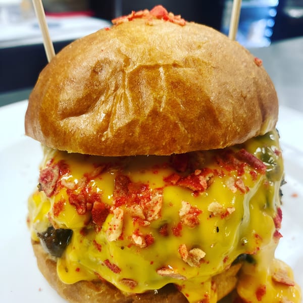 A Rock Burger with melted cheese and red crispy toppings, held together by two toothpicks.