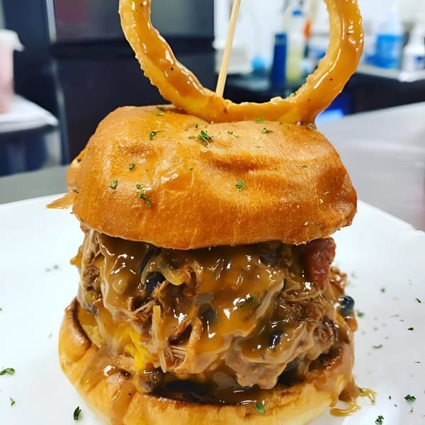 Rock Burger's pulled pork burger with melted cheese, onions, mushrooms, and a large onion ring.