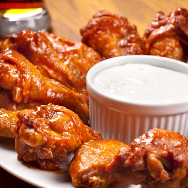 Rock Burger's buffalo wings, glistening with sauce, served with a side of creamy ranch dip.