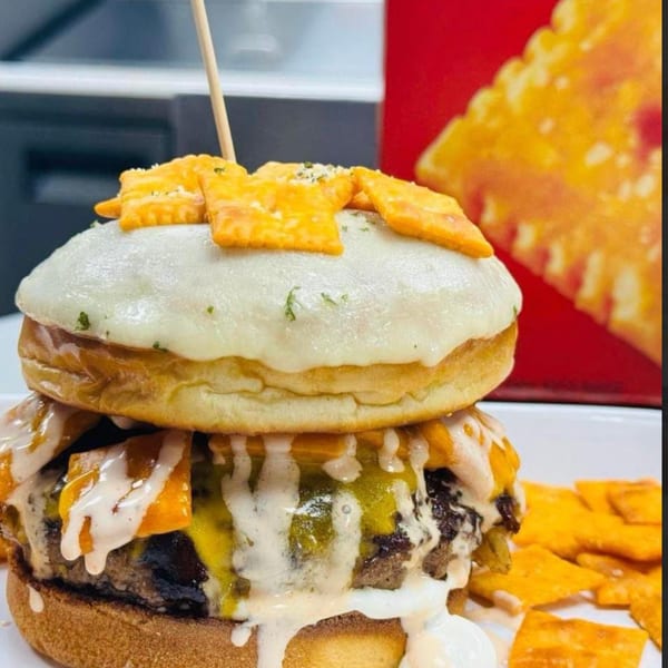 A Rock Burger with melted cheese, sauce, and cheese crackers on top and around it.